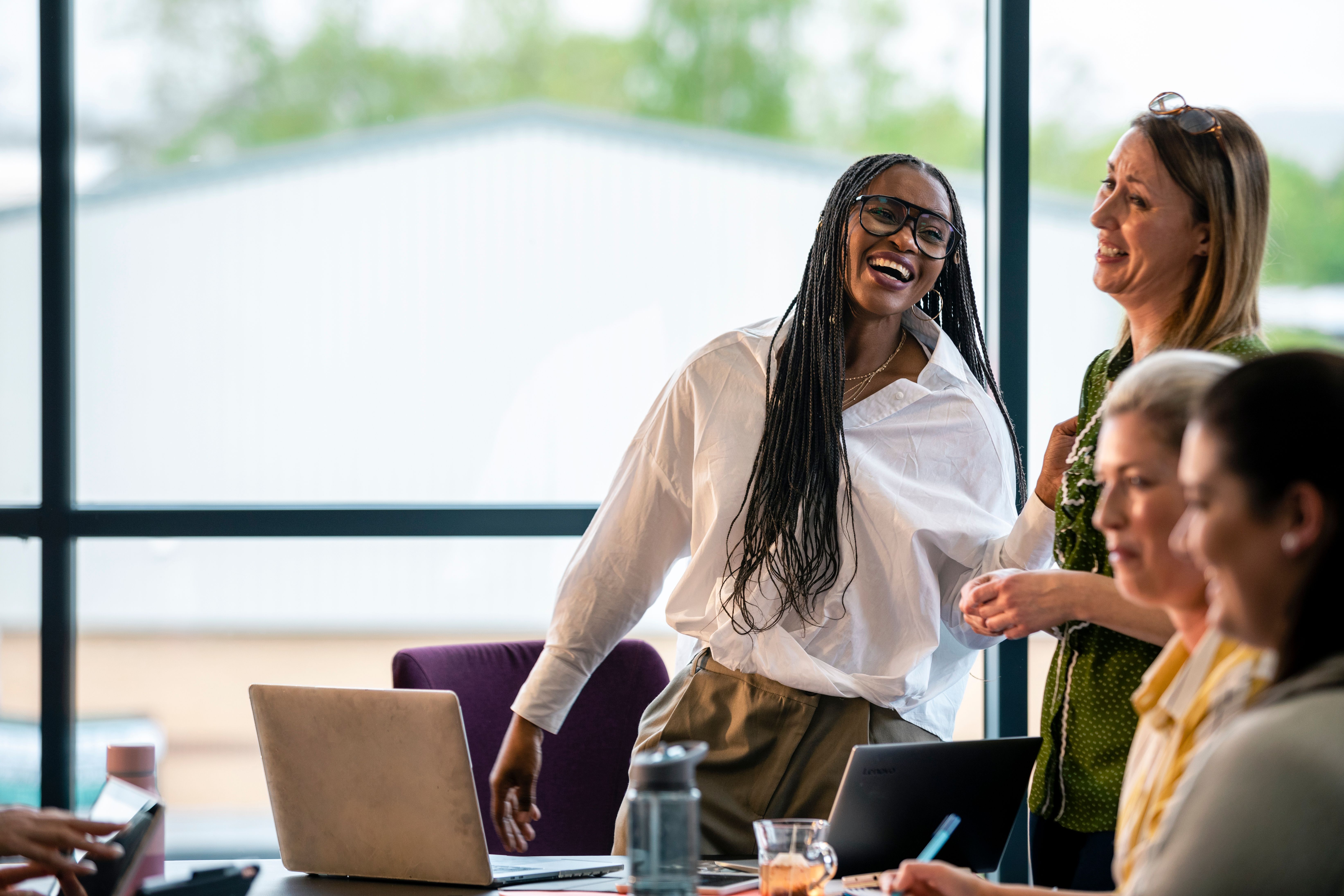 Colleagues smiling and chatting during a team meeting in an office.