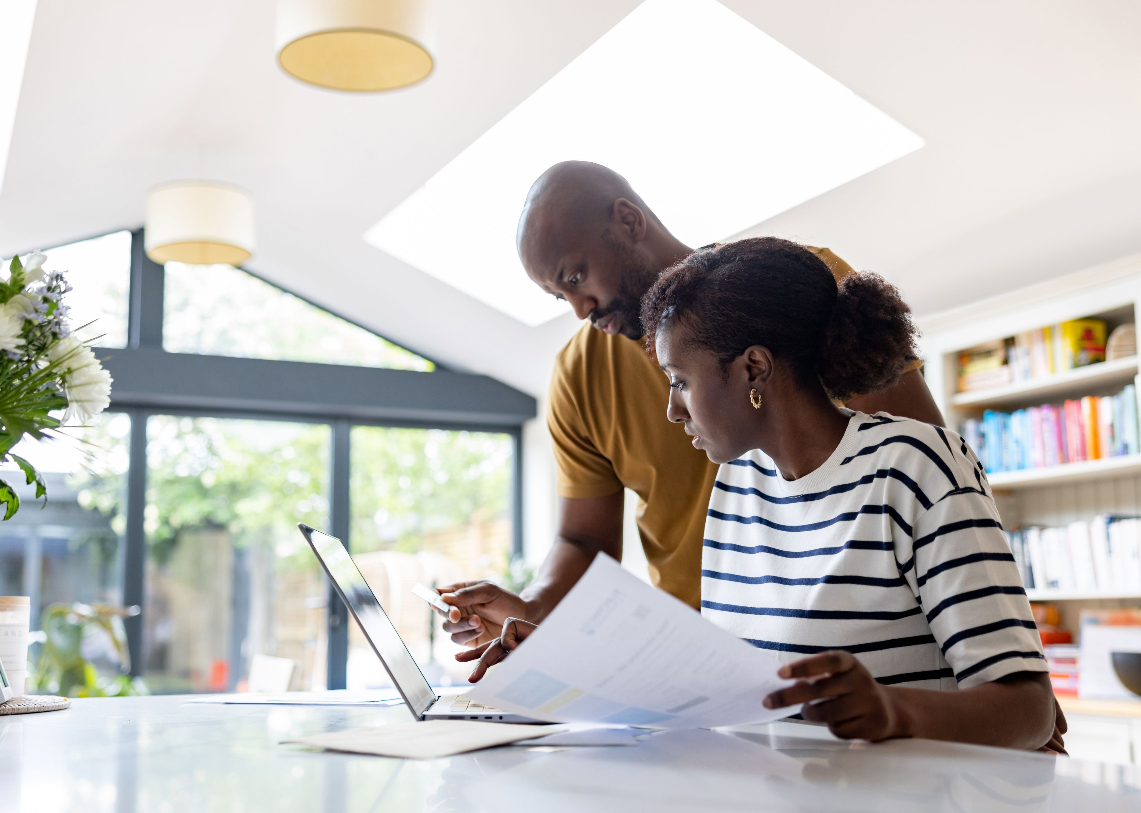 Two people reviewing documents at a laptop.