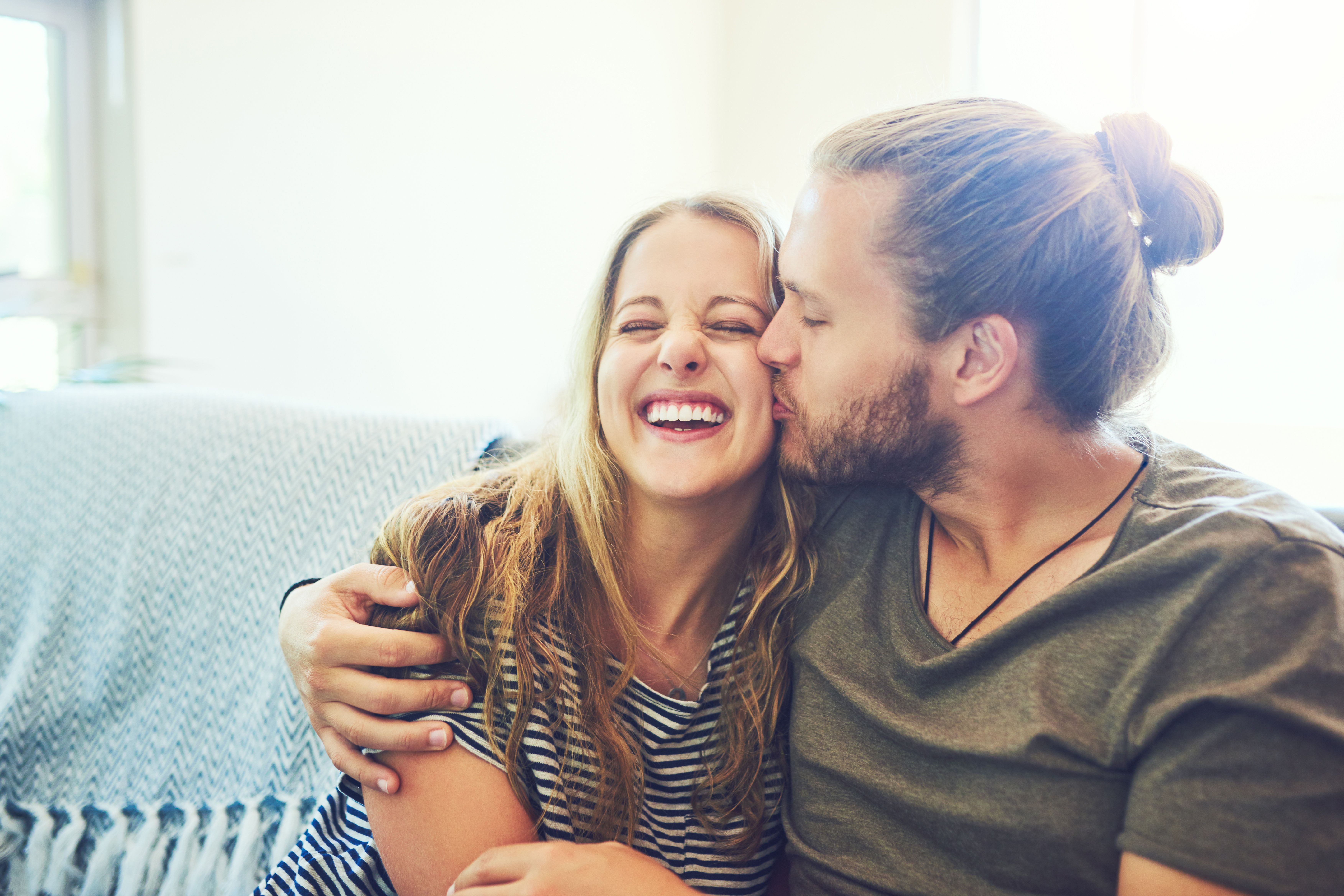 Young man and woman smiling and cuddling on a sofa
