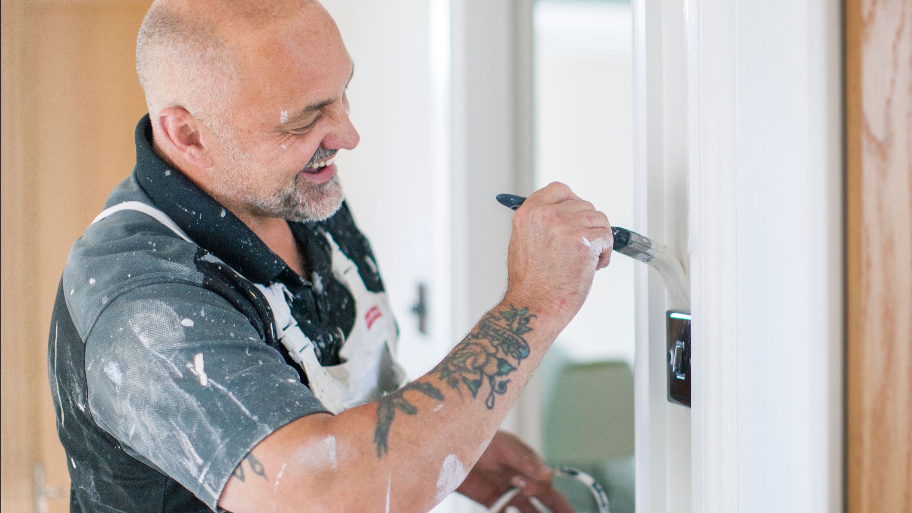 A painter applies paint to a door frame indoors