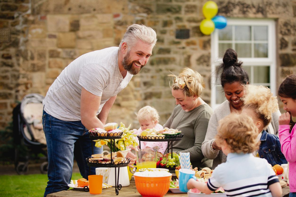 Over-50 grandfather enjoying a family gathering with children and grandchildren outdoors.