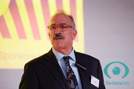 Tom Baigrie giving a speech wearing suit and tie