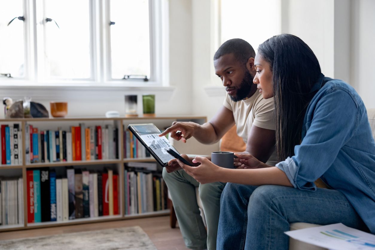 Man and woman sitting together on a sofa looking at a laptop. 