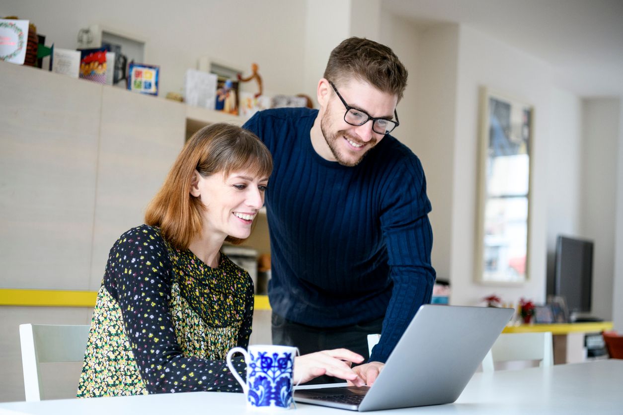 Man and woman looking at a laptop together smiling.